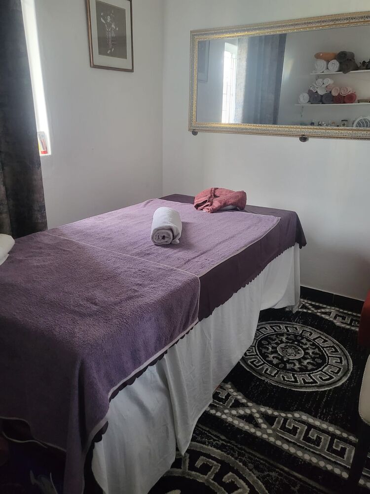Massage treatment room with a purple-draped bed and warm towels